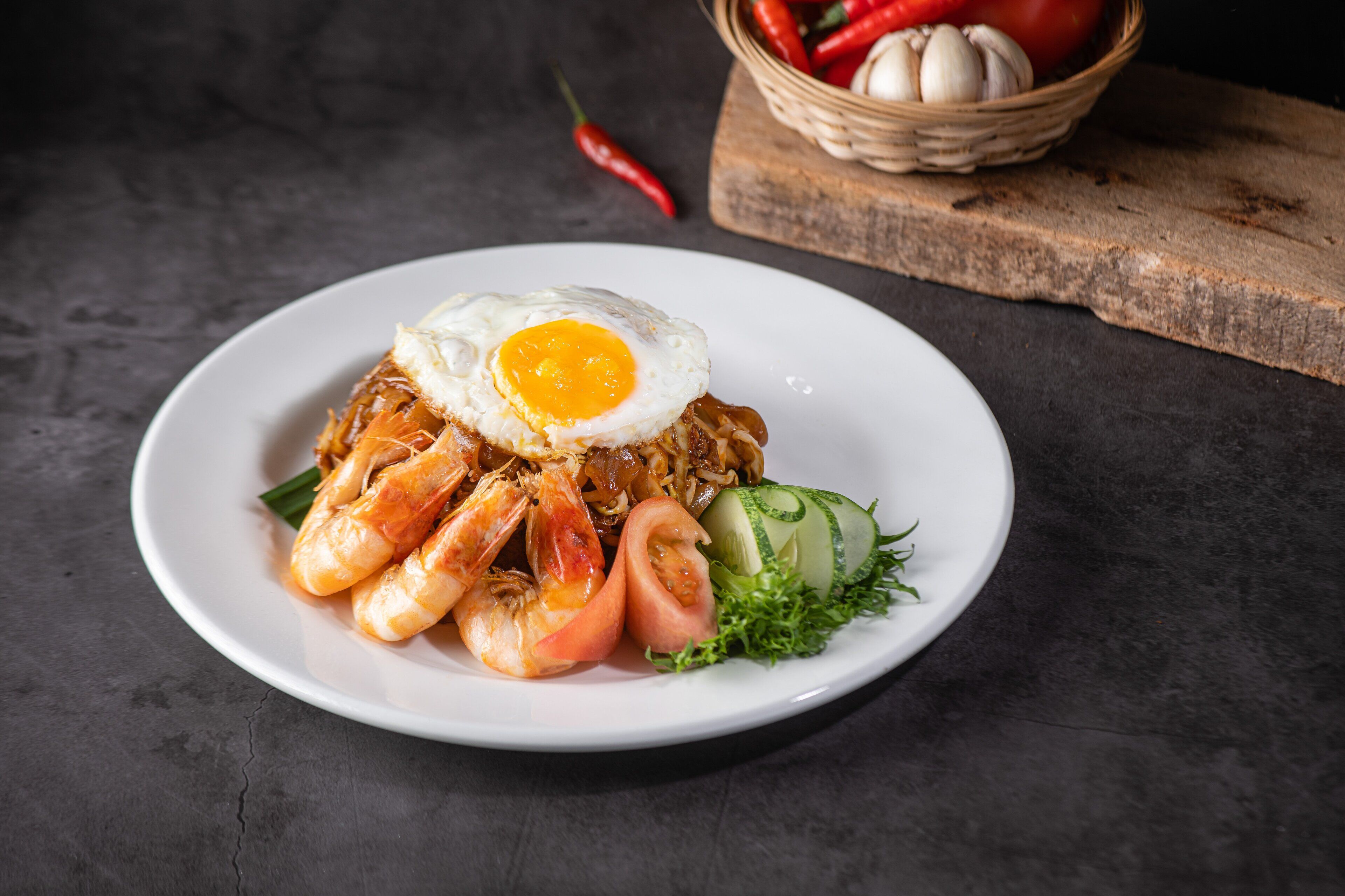 Une assiette de nourriture comprenant des crevettes, un œuf frit et des légumes.
