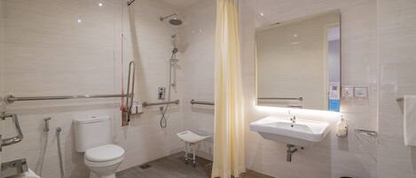 A modern bathroom with a toilet, shower, and sink.
