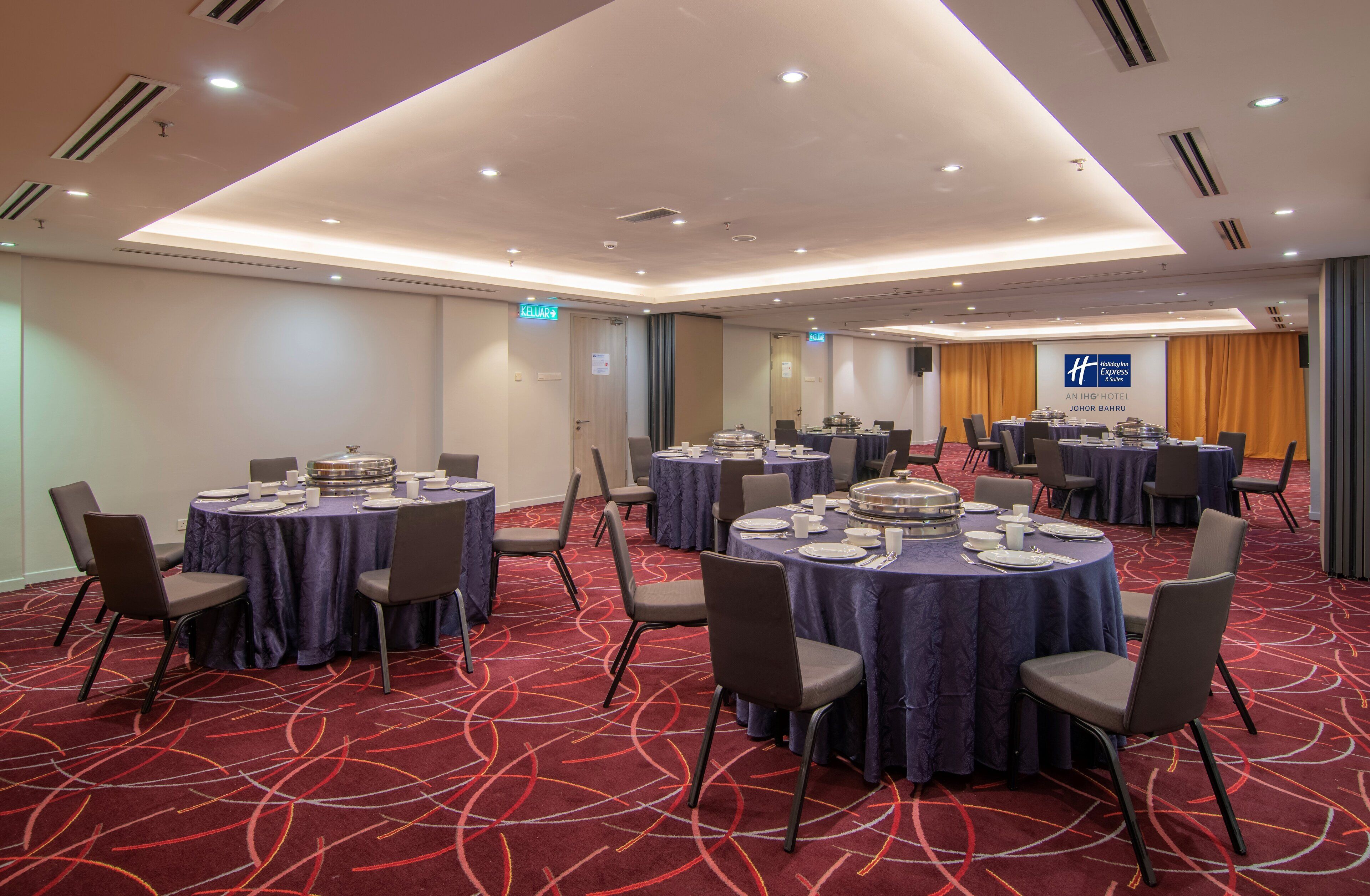 A conference room with multiple round tables, each set with plates, cups, and a centerpiece. The room has a red carpet, recessed lighting, and a sign for the Anling Hotel.