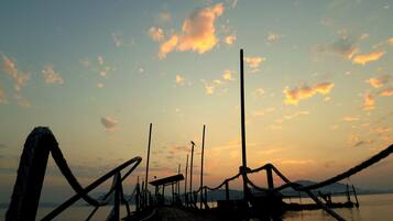 A wooden pier extending into calm water with a sunset in the background.
