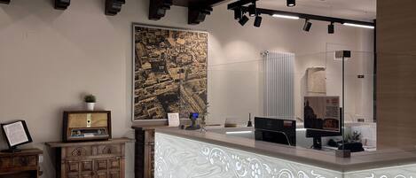A reception area with a marble counter, wooden furniture, a large cityscape painting, and modern lighting fixtures.