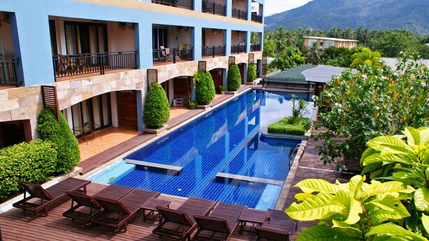 A hotel with a swimming pool, multiple balconies, and lush greenery. - Victorian Samui Condominium (Koh Samui)
