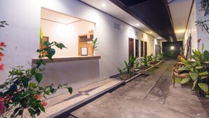 Un pasillo con un banco, plantas en macetas y una estructura de madera.