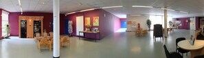 A spacious indoor area with a curved ceiling, a vending machine, a table with chairs, and a bulletin board with various notices. - Ethic Etapes Cis Besançon (Besancon)
