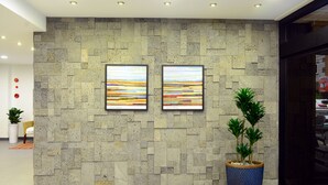 A lobby with a stone wall, two framed artworks, and a potted plant. - Casa Mini Hotel (Gyeongju)