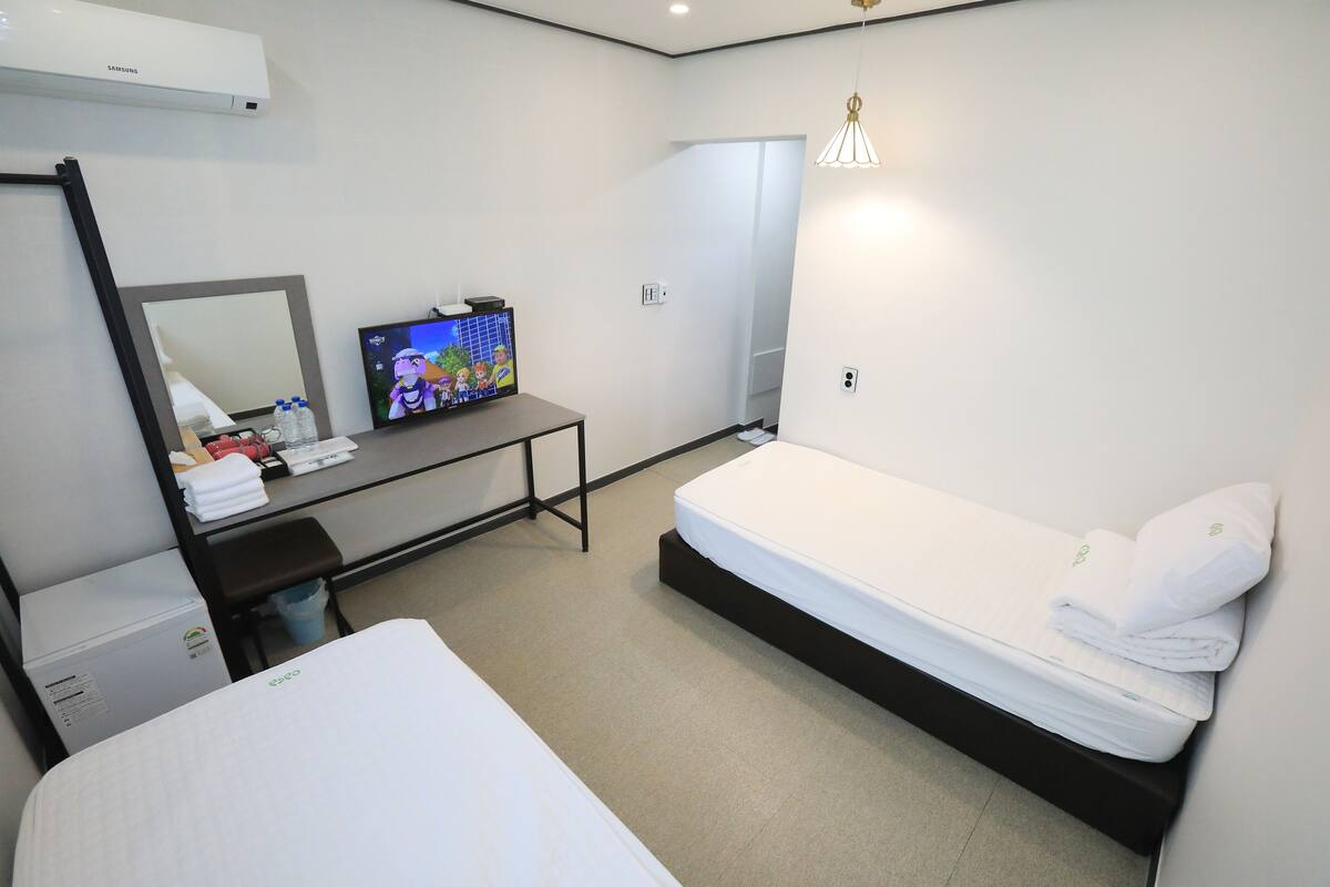 Una habitación de hotel con una cama, un escritorio con una computadora, un espejo y un aire acondicionado de pared.
