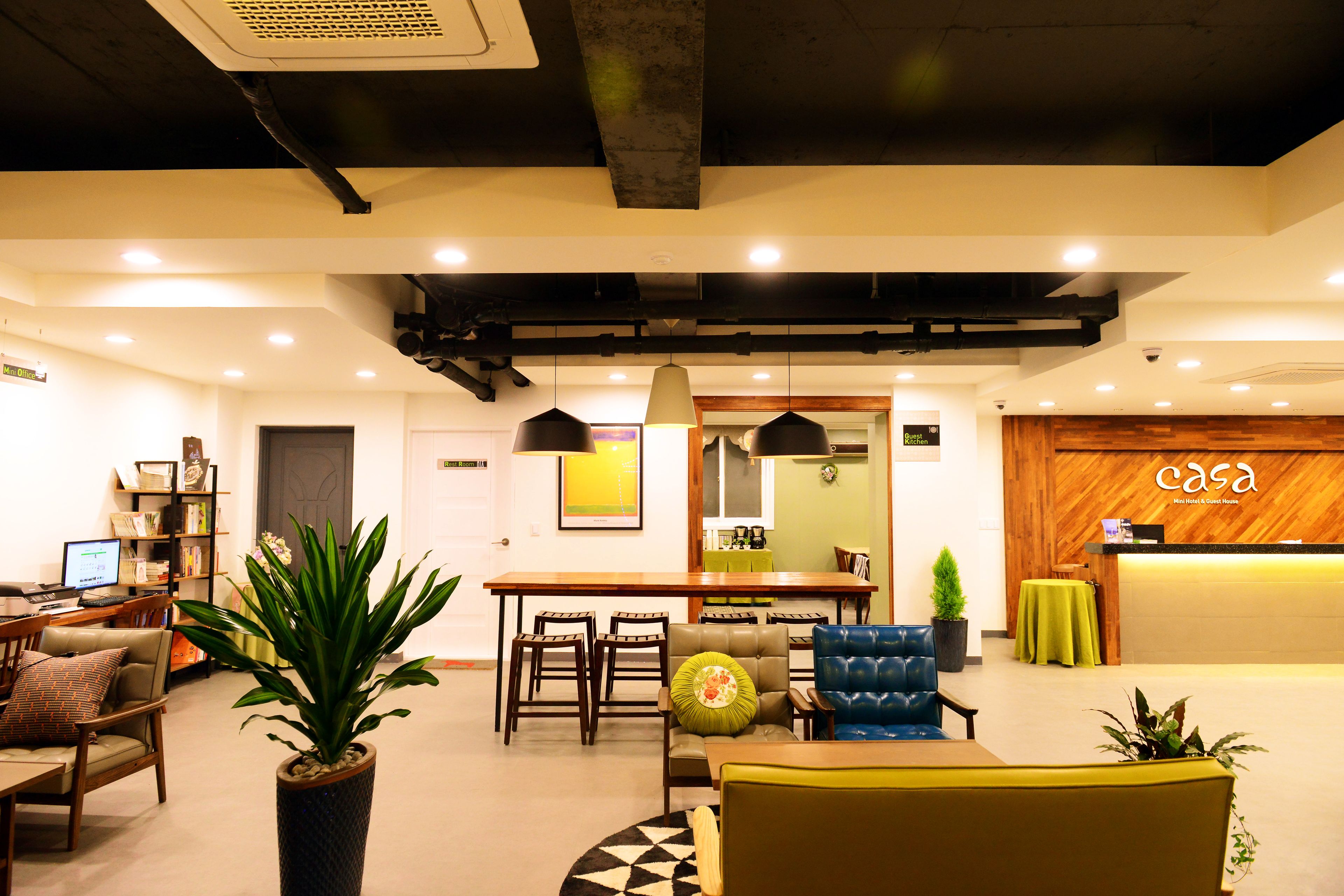 Un hall d’hôtel moderne comprenant un comptoir d’accueil, un espace salon et un espace repas.