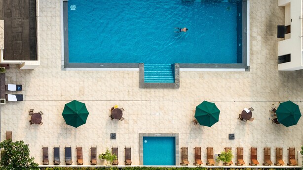 An aerial view of a swimming pool with a person swimming, surrounded by lounge chairs and umbrellas, and a door labeled "290".