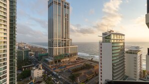 A high-rise building with a glass facade, adjacent to a body of water, and surrounded by other modern buildings.