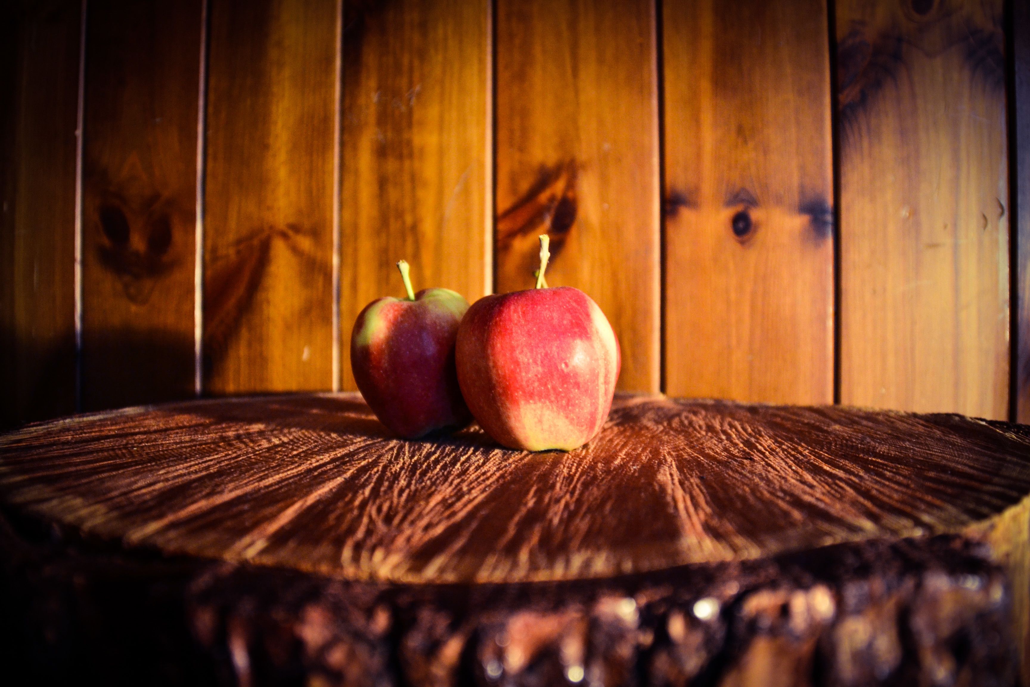 Two apples on a wooden surface with a wooden background.