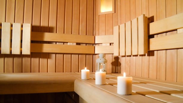 A wooden sauna with benches and three lit candles. - Hotel Vecchia America (Dimaro Folgarida)