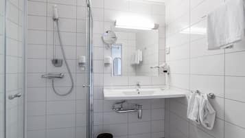 Une salle de bain moderne avec une douche à l’italienne en verre, un lavabo blanc et un miroir.