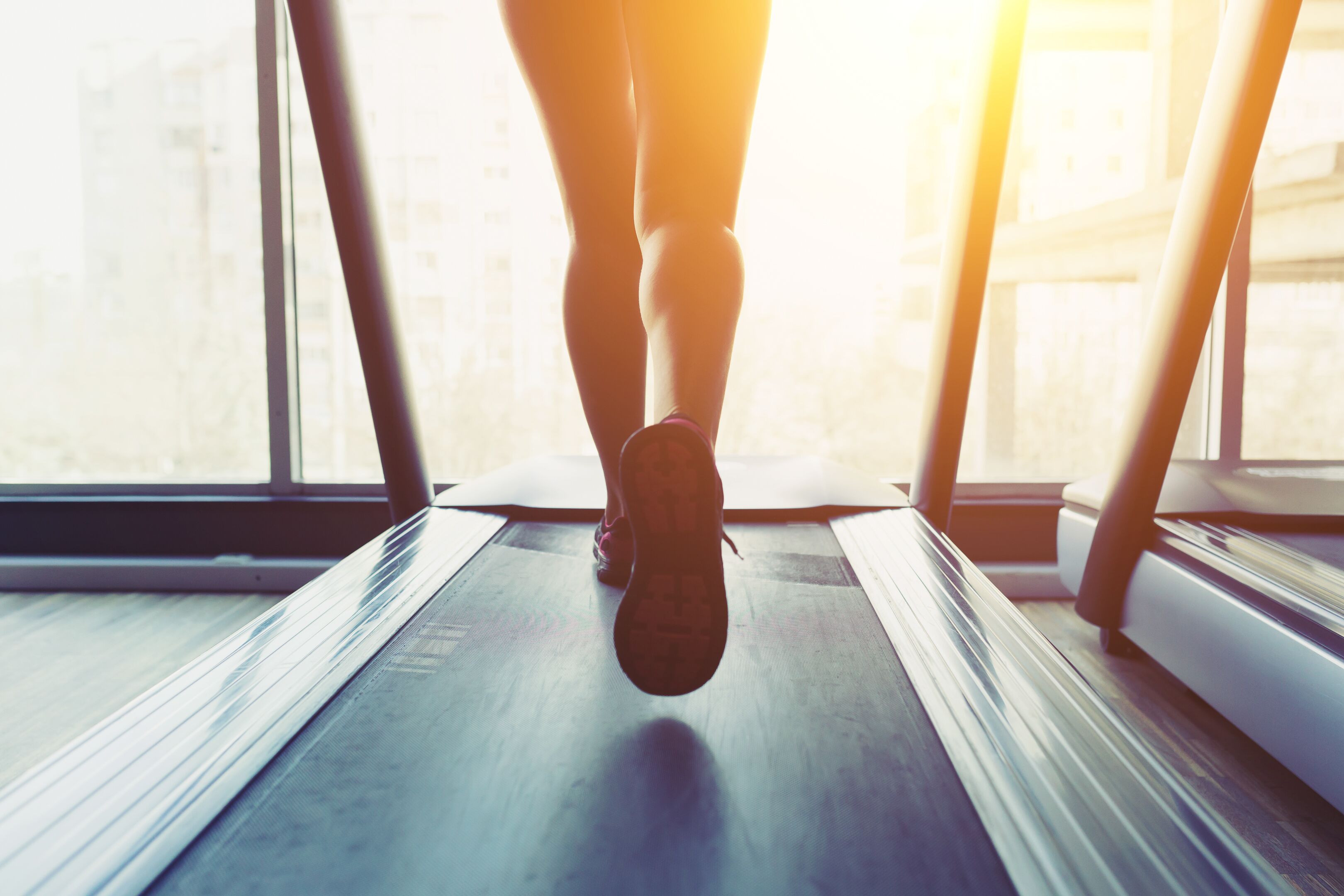 A treadmill in a gym with a view of a building outside.