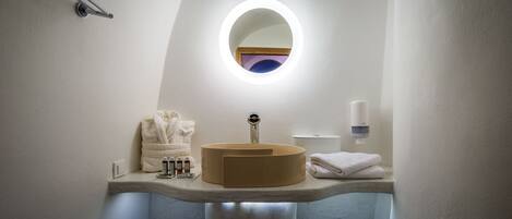 A bathroom with a round mirror, a sink, and a towel rack.