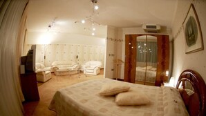 A bedroom with a large bed, a mirror, a dresser, and a seating area with chairs and a table. - Hotel Mirage (Burgas)