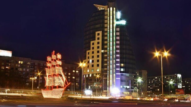 A nighttime cityscape with illuminated buildings and a large ship-like structure in the foreground. - Hotel Mirage (Burgas)