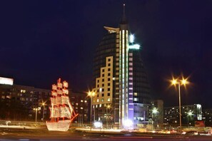 A nighttime cityscape with illuminated buildings and a large ship-like structure in the foreground. - Hotel Mirage (Burgas)