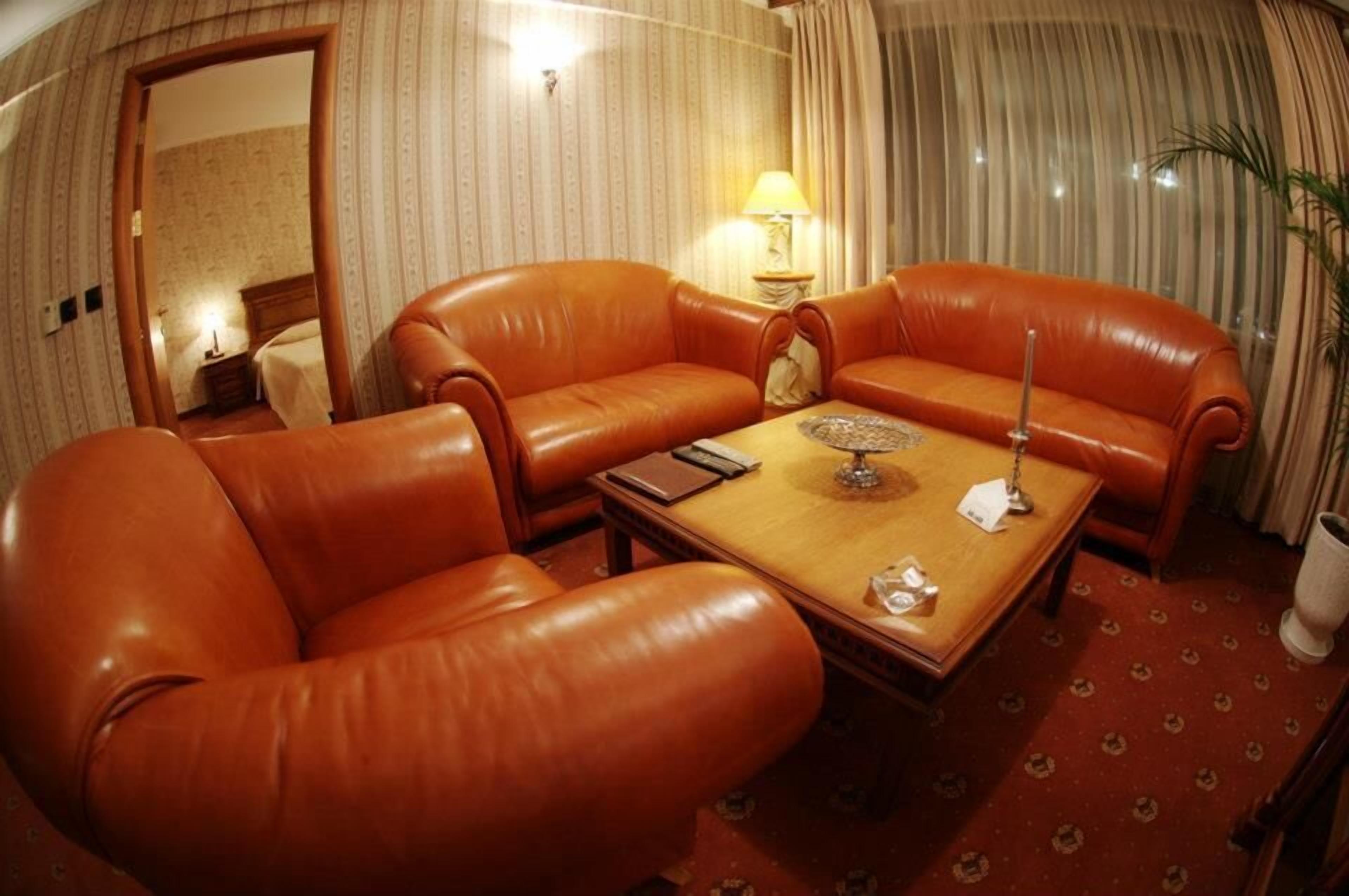 A room with a brown leather sofa set, a wooden coffee table, and a lamp.