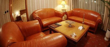 A room with a brown leather sofa set, a wooden coffee table, and a lamp.