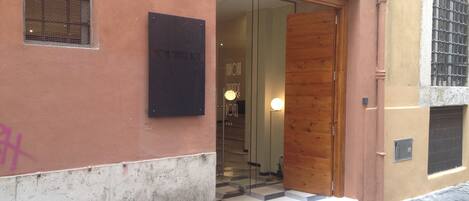 A hotel entrance with a glass door, a signboard, and a checkered floor.