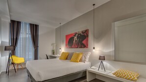 A modern hotel room with a large bed, bedside tables, a desk, a chair, and a large window with curtains. - Navona Theatre Hotel (Rome)