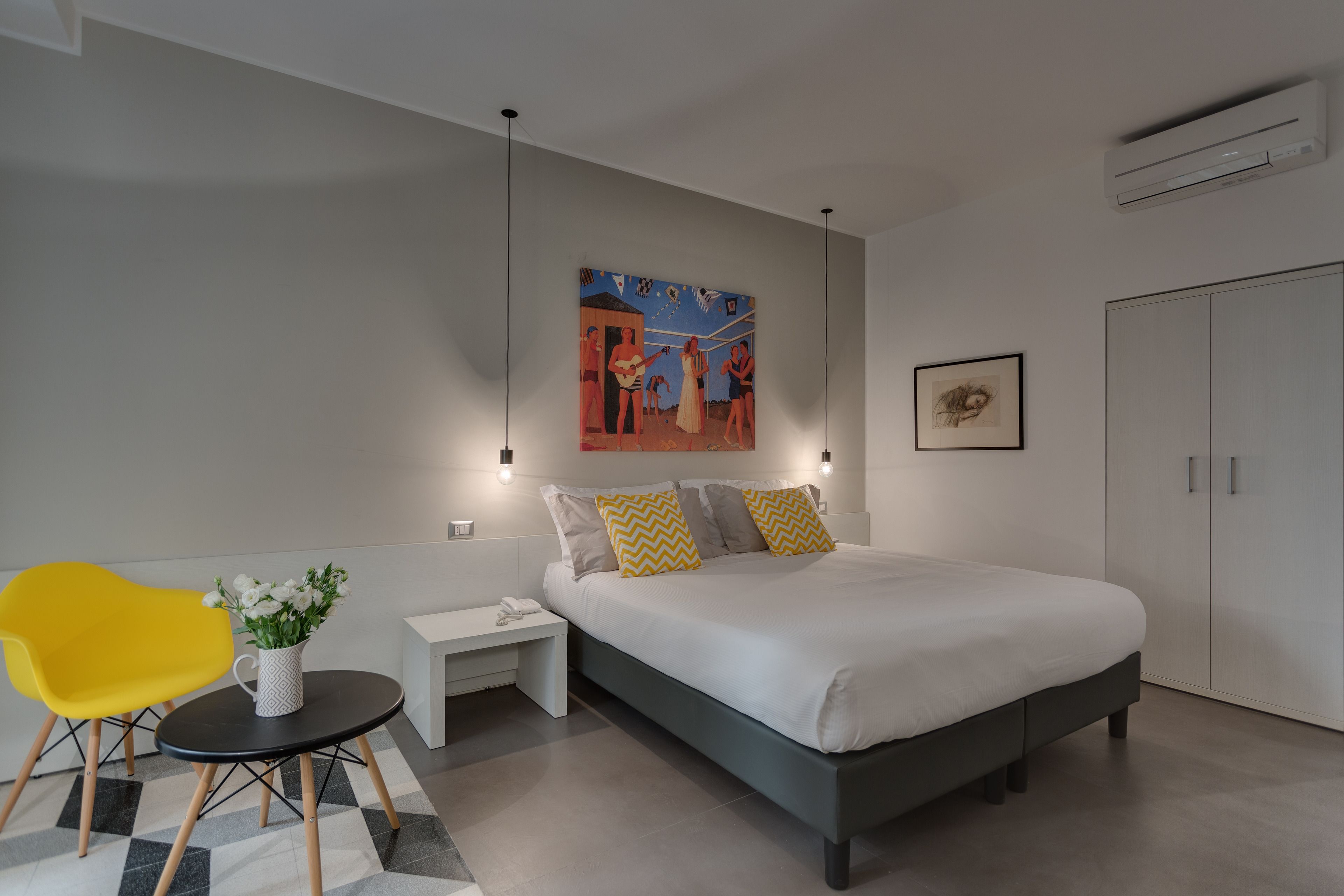 A modern bedroom with a large bed, a bedside table, a chair, and a painting on the wall.