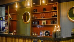 A bar area with shelves stocked with bottles, a record player, and hanging light fixtures. - Dansaert Hotel (Brussels)