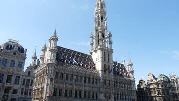 A historic building with intricate architecture, multiple flags, and a prominent tower.
