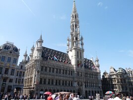 A historic building with intricate architecture, multiple flags, and a prominent tower.