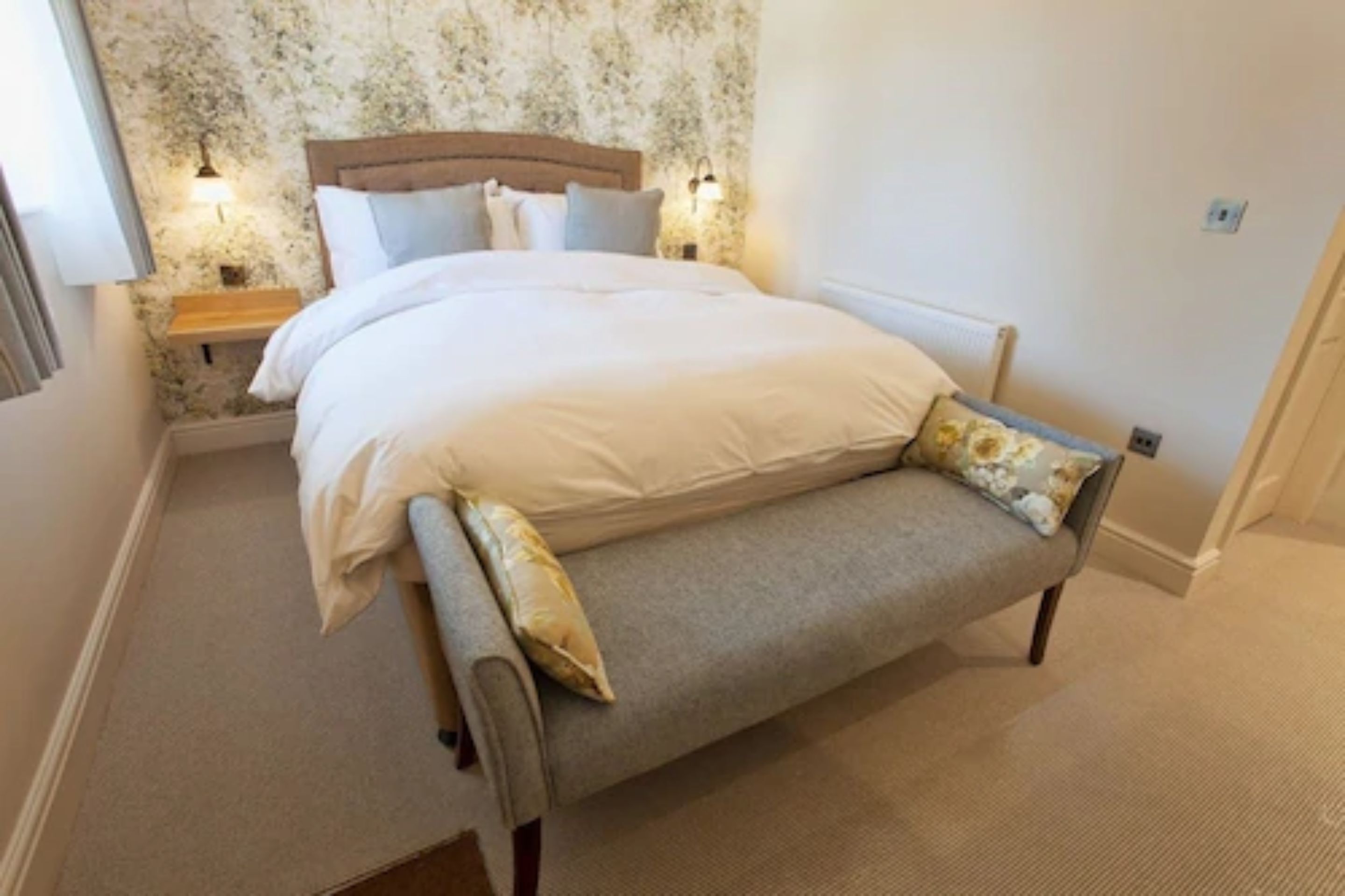A bedroom with a bed, bedside tables, and a bench.