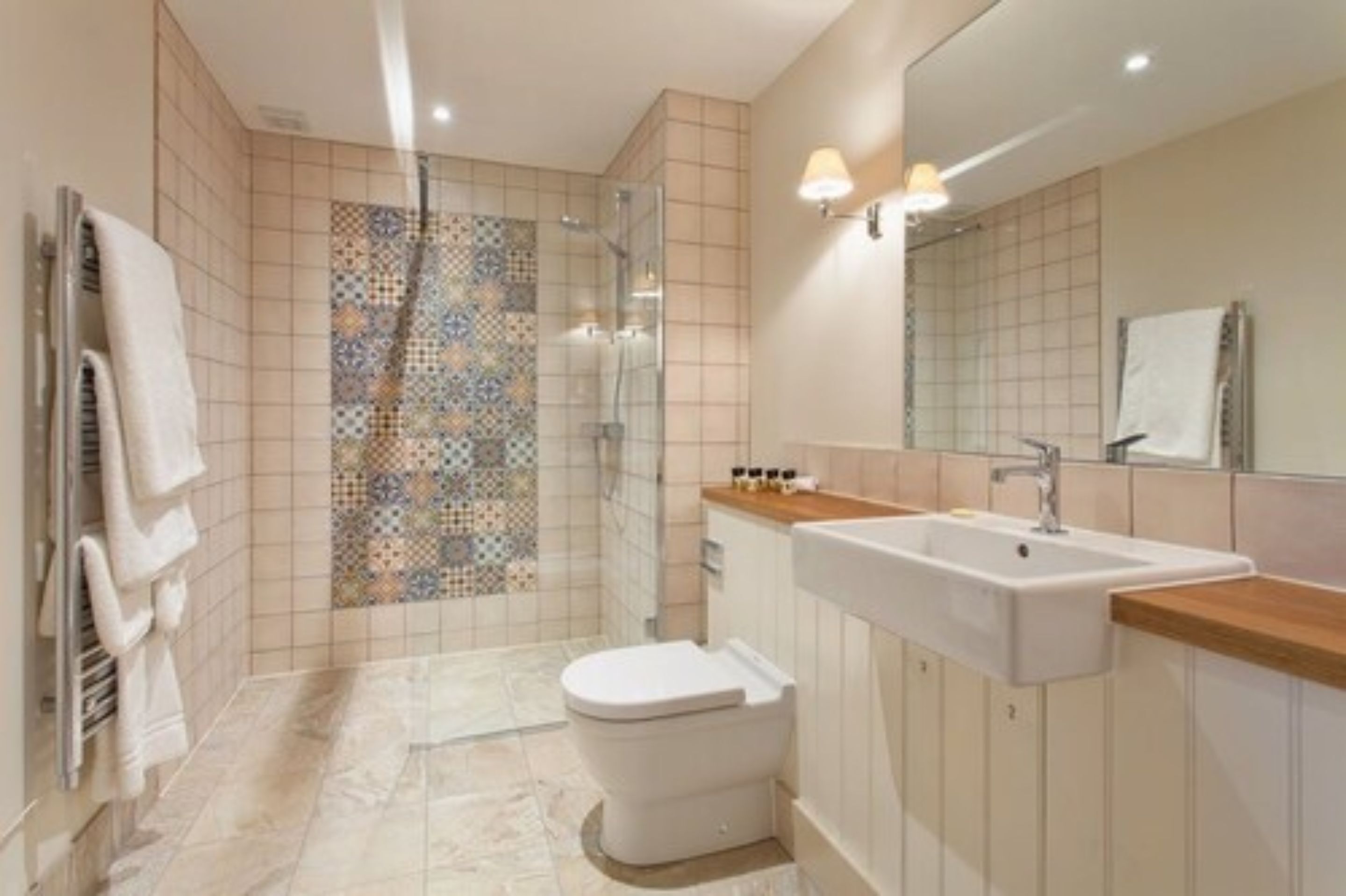 Un baño con ducha, inodoro, lavamanos y paredes de azulejos.