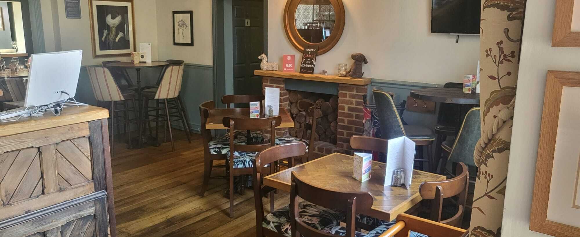A cozy restaurant with wooden furniture, a fireplace, and a TV mounted on the wall.