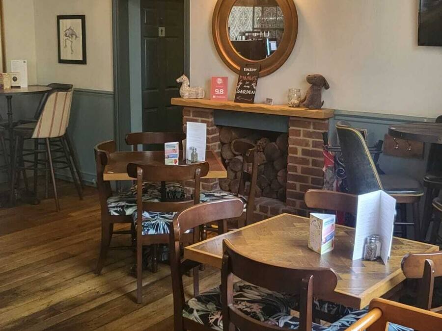 A cozy restaurant with wooden furniture, a fireplace, and a TV mounted on the wall.