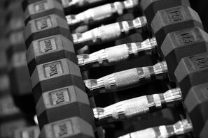 A close-up of a row of hexagonal dumbbells with weight markings. - Heden Golf Hotel (Abidjan)