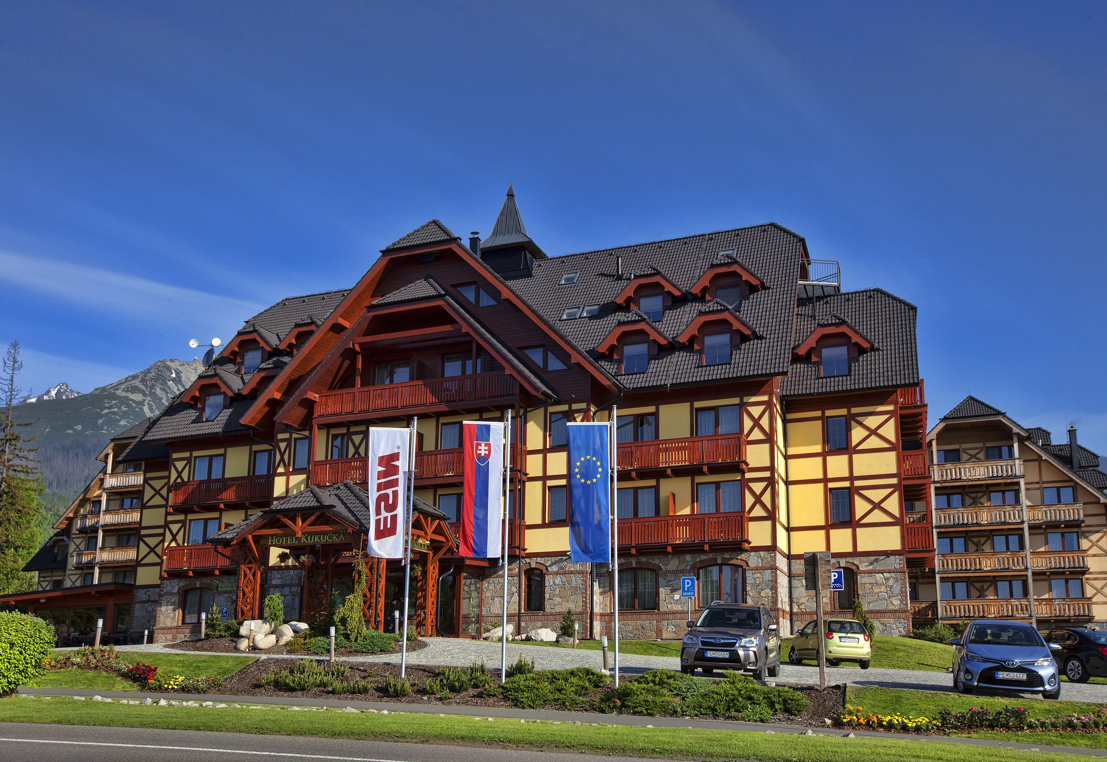 Un hôtel à plusieurs étages, de style architectural alpin traditionnel, doté de balcons et d’une façade en pierre.
