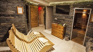 A spa room with a wooden bench, stone walls, a wooden dresser, and a television mounted on the wall. - APLEND Hotel Kukučka a Rezidencie (Vysoké Tatry)