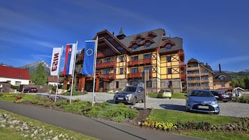 Un hotel de arquitectura tradicional, con varios balcones y un estacionamiento.
