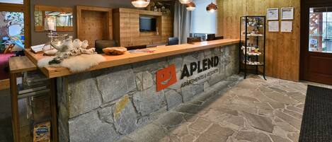 A reception area with a stone counter, wooden paneling, and pendant lighting.