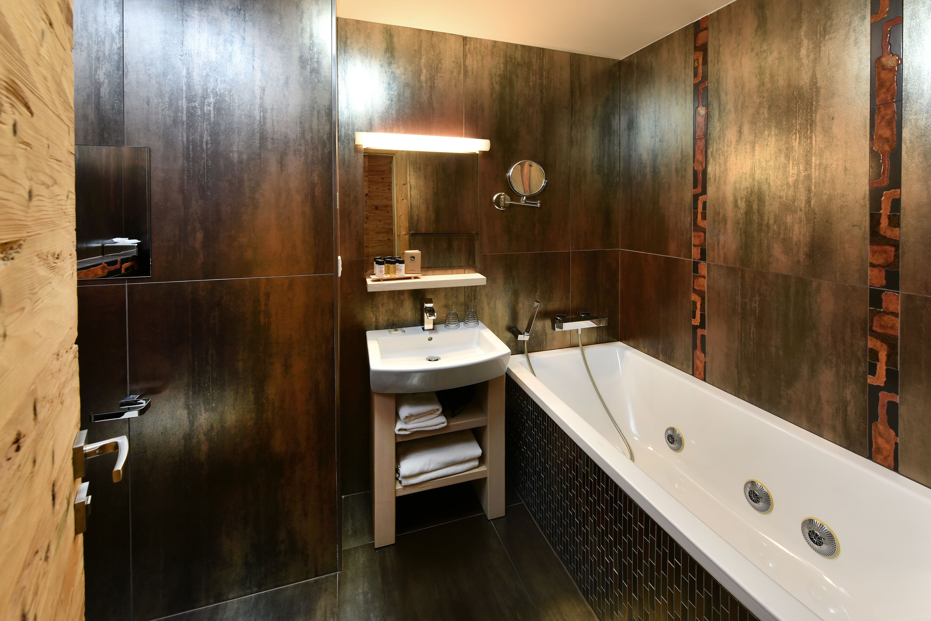 Un baño moderno con tocador de madera, lavamanos y bañera.