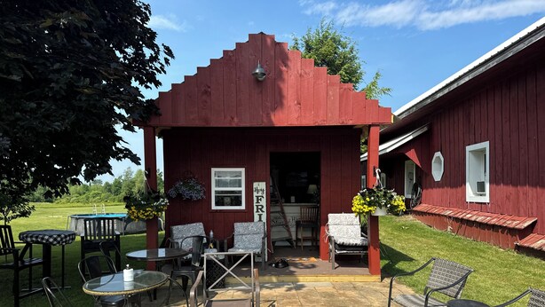 A red wooden structure with a covered patio area, outdoor seating, a fire pit, and a pool. - Northern Family Motel (Potsdam)