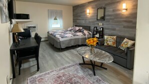A modern bedroom with a bed, bedside table, lamp, and a small round table with flowers. - Northern Family Motel (Potsdam)