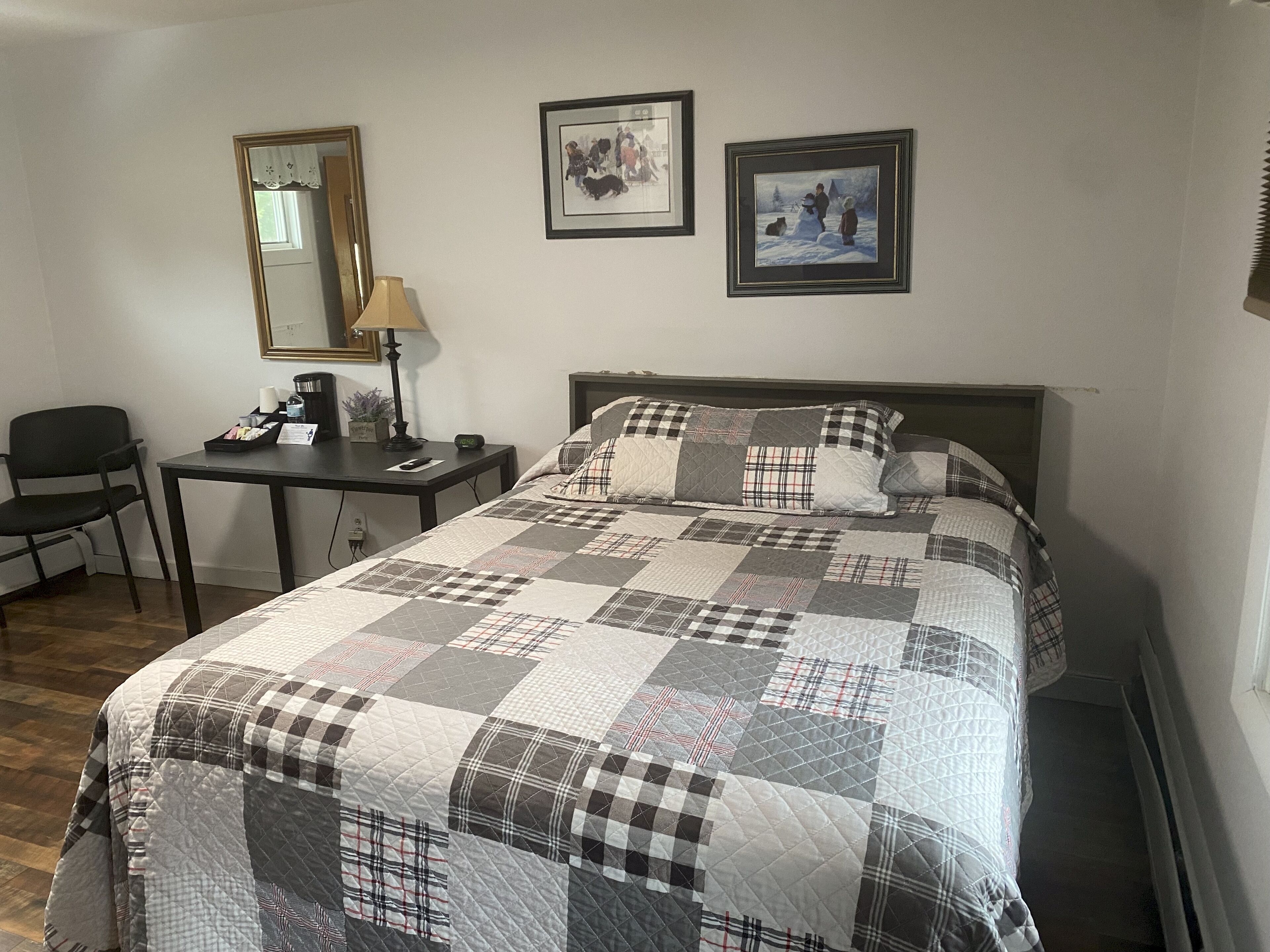 Un dormitorio ordenado con cama, escritorio y silla. Hay dos cuadros en la pared.