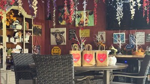 A cozy cafe with wicker chairs, a round table, and various decorations including hanging flowers and wall art. - Northern Family Motel (Potsdam)