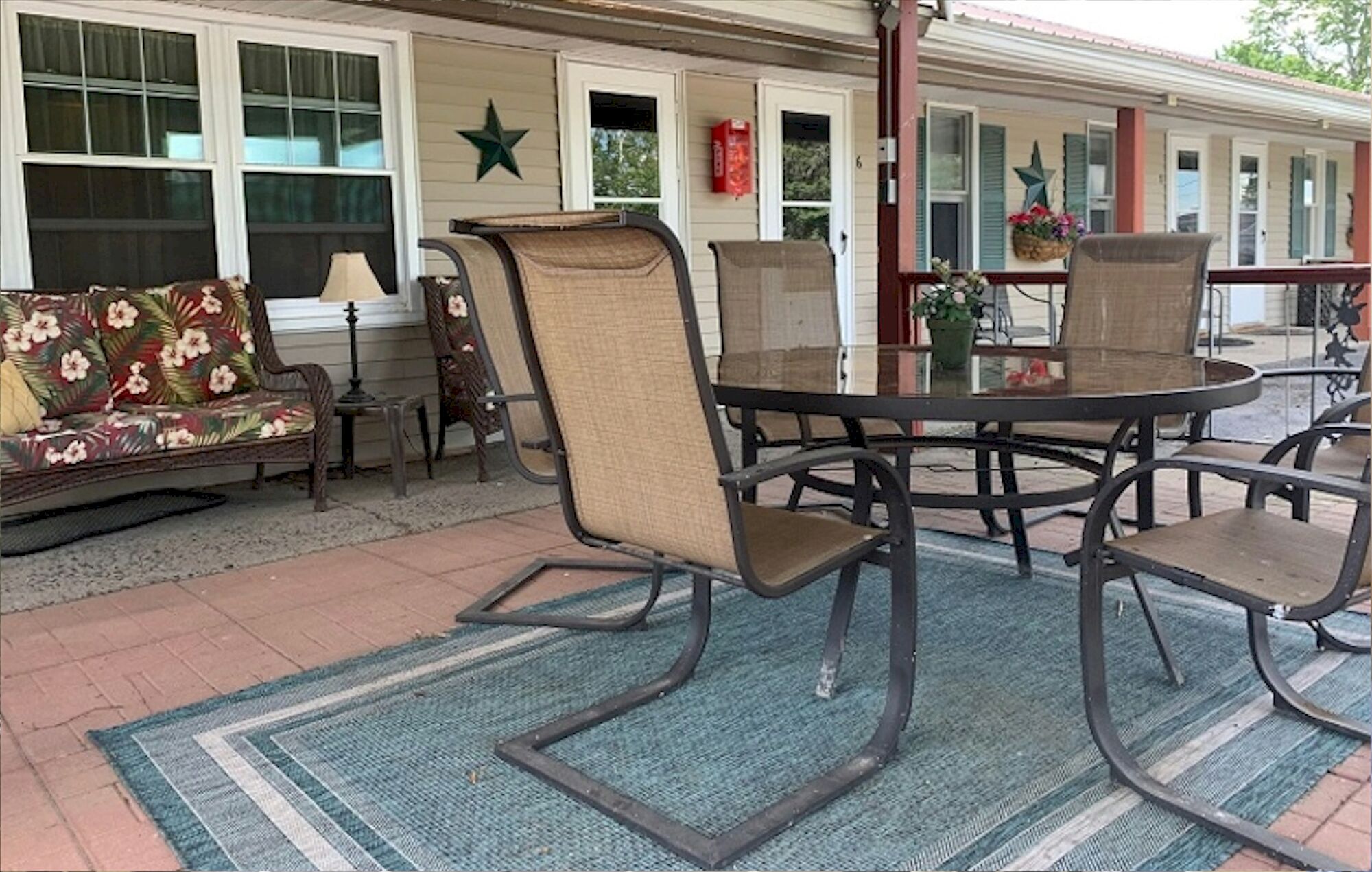 A patio with a round table and four chairs, a sofa, and a lamp.