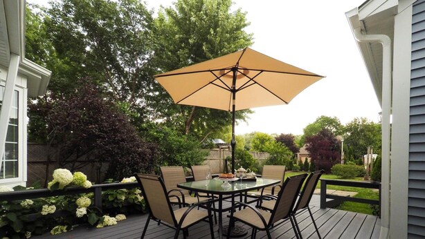 Una terrazza con tavolo e sedie, un ombrellone e vista sul giardino.