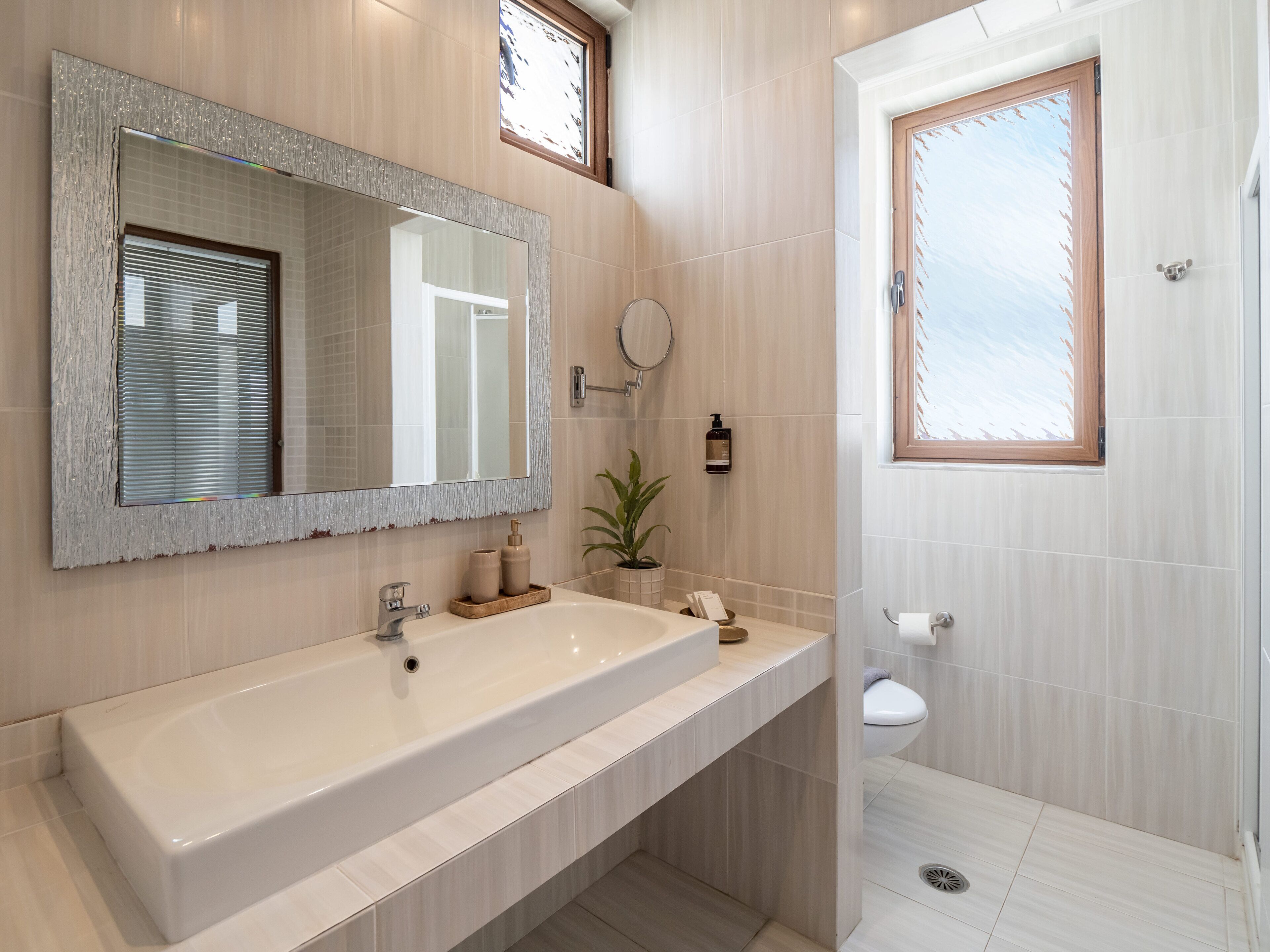 Une salle de bain moderne avec un grand lavabo, un miroir, des toilettes et un espace douche.