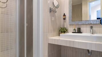 Une salle de bain moderne avec une douche à l’italienne, un grand miroir et un lavabo blanc.