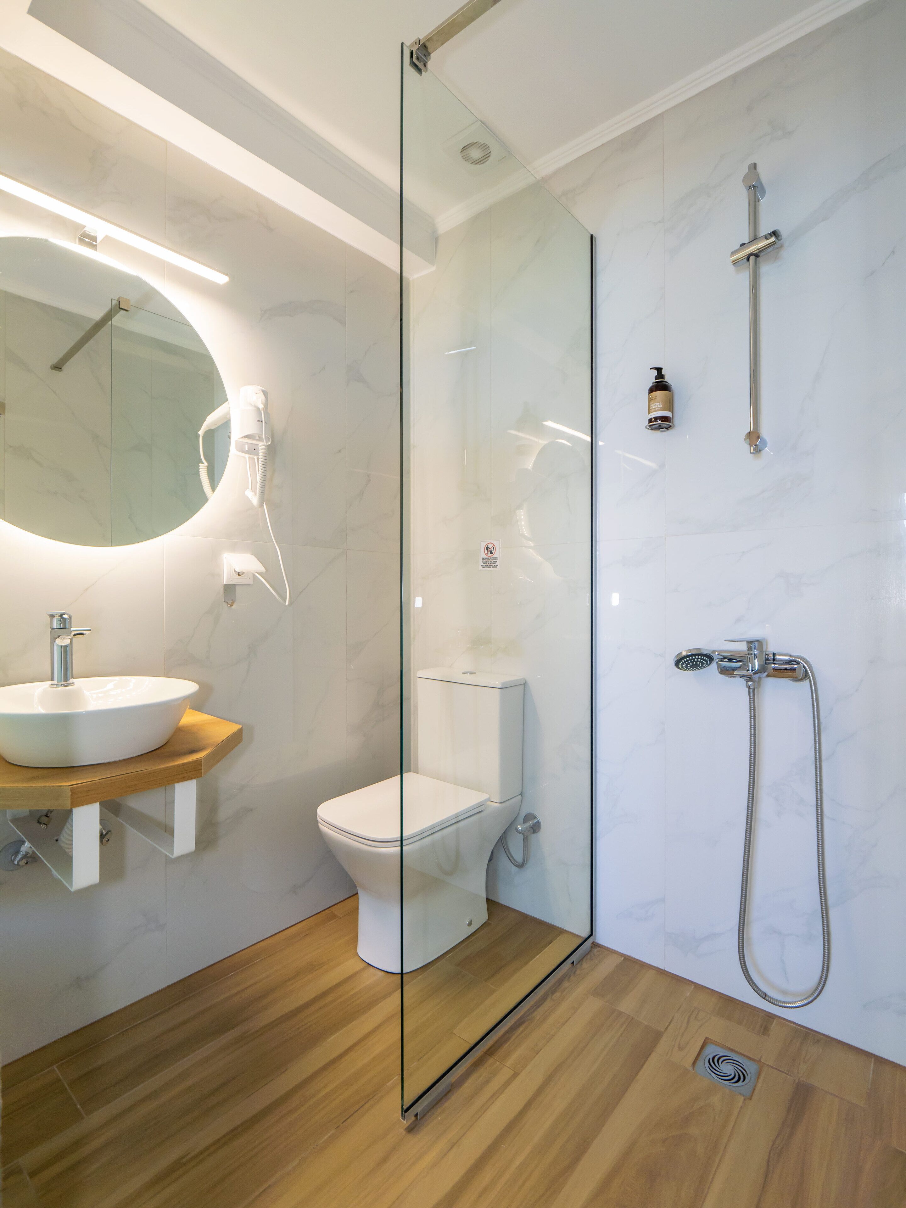 A modern bathroom with a glass-enclosed shower, a wooden vanity with a sink, and a toilet.