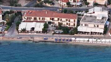 A coastal building with multiple balconies, a terrace with umbrellas, and a view of the sea.