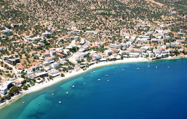 Vista aérea de un pueblo costero con edificios a lo largo de la costa y barcos en el agua.